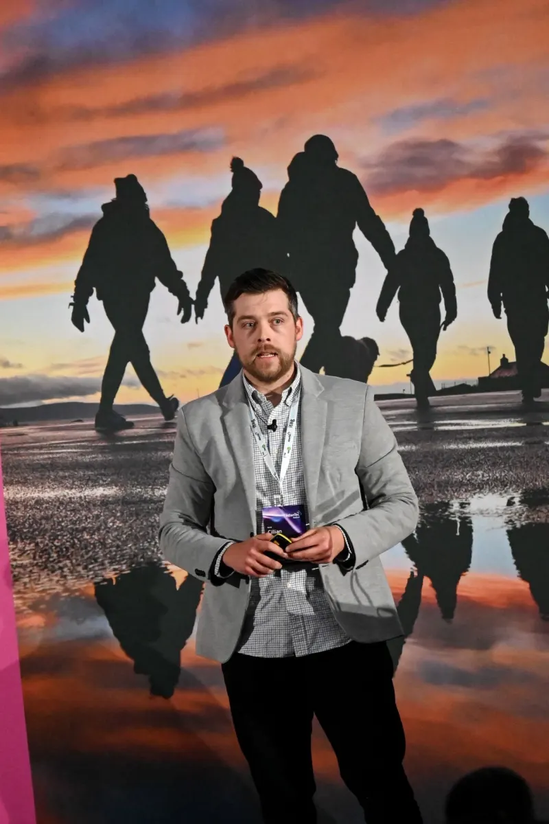 Cillian speaking on stage at itag AtlanTec, in front of a sunset backdrop